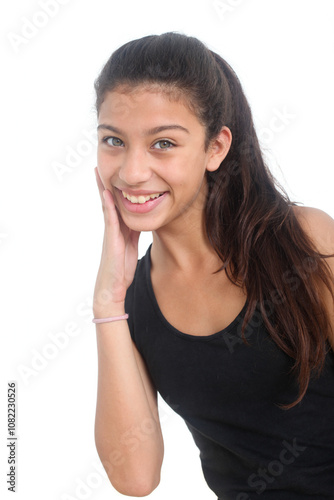 portrait of cheerful latino teenage girl touching her face and smiling on white background