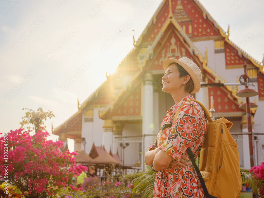 Fototapeta premium Travel to Ayutthaya, Thailand. Young female tourist explores modern Buddhist temples, surrounded by vibrant architecture and cultural symbols, capturing essence of spirituality and Thai heritage.