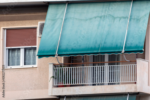 close up on the facade of an apartment building in Athens, Greece with green awnings. 