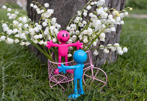 white lilies of the valley in souvenir toy metal bicycle. funny souvenir figures are happy to meet. couple in love, concept of romance, love and tender feelings, romantic surprise , flowers with love photo