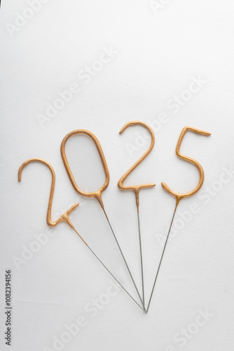 Numbers 2025 made from golden sparklers on white background. Celebrating New Year, close-up. Vertical frame.