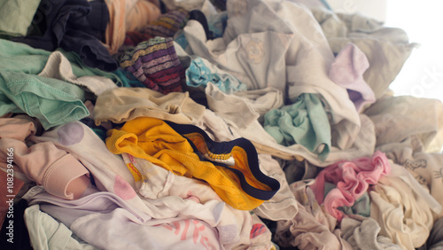 Big pile of clean clothes lying on a couch, laundry waiting to be folded