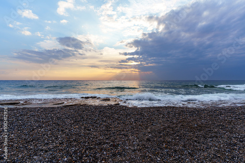 Fototapeta Naklejka Na Ścianę i Meble -  Serene Pebble Beach at Sunset with Radiant Sky and Ocean Waves..