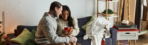 Tableau sur toile A couple shares a warm embrace while sipping drinks together during the festive season at home