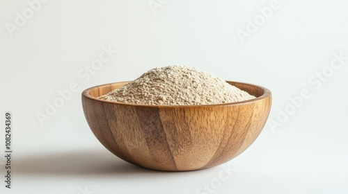 A wooden bowl filled with wheat flour, set against a plain white backdrop.