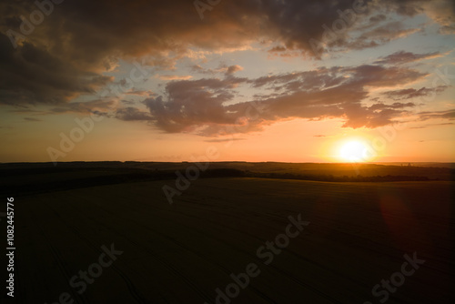 Aerial landscape view of yellow cultivated agricultural field with ripe wheat on vibrant summer evening