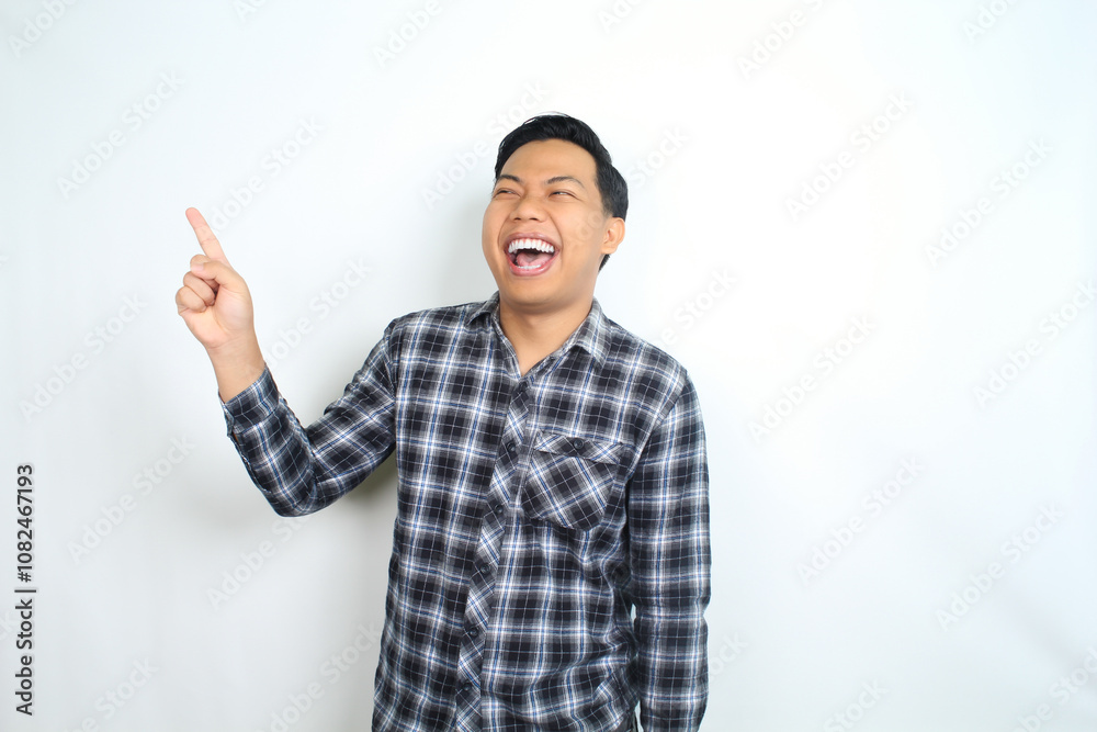carefree asian man pointing hand with laughing expression showing joy and playful emotion wearing casual plaid shirt isolated on white background carefree asian man pointing hand with laughing expression showing joy and playful emotion wearing casual plaid shirt isolated on white background