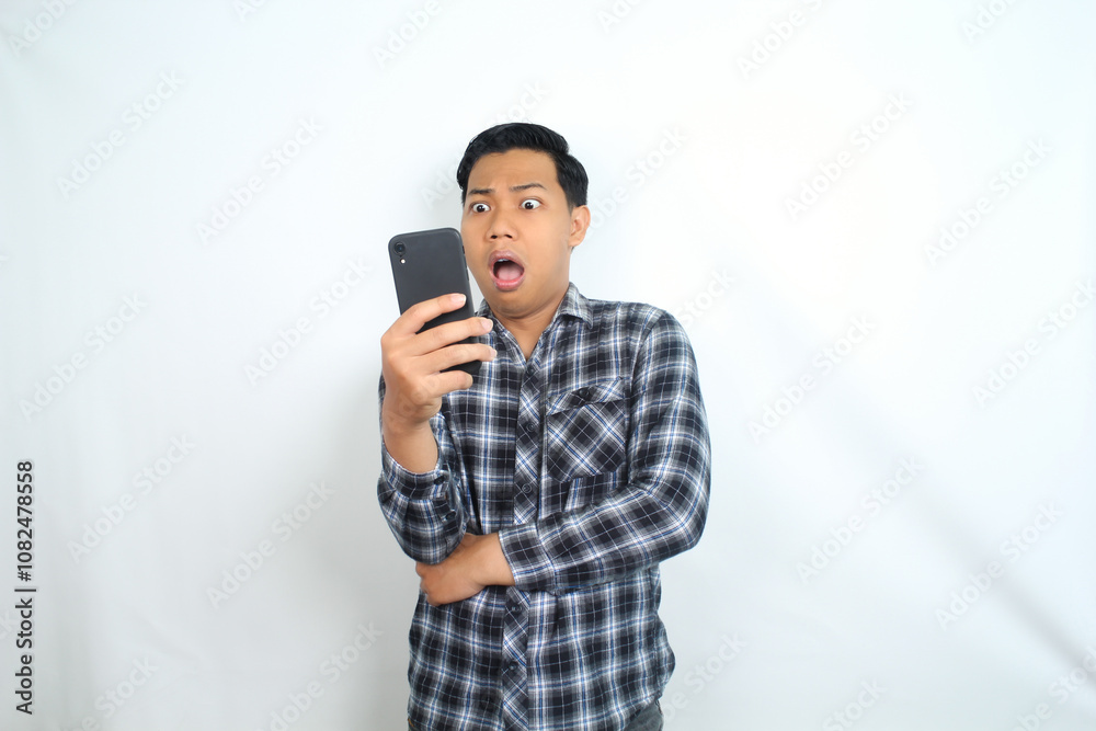 asian man shocked looking at smartphone isolated on white wearing casual shirt asian man shocked looking at smartphone isolated on white wearing casual shirt