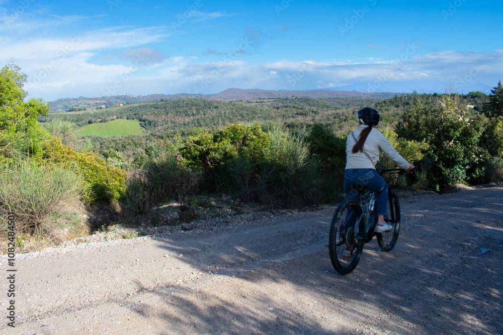 Female on Electric Bike taking a trail ride through Tuscany Italy Female on Electric Bike taking a trail ride through Tuscany Italy