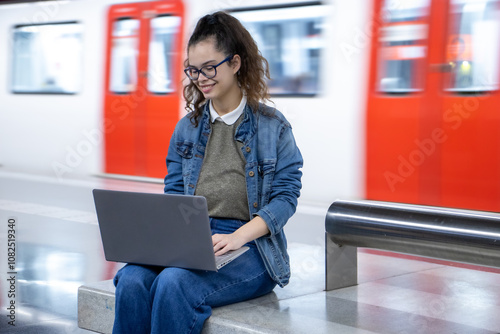 Girl waiting for the train and using her laptop