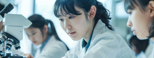 Asian Female Scientist Using Microscope with Team in Laboratory
