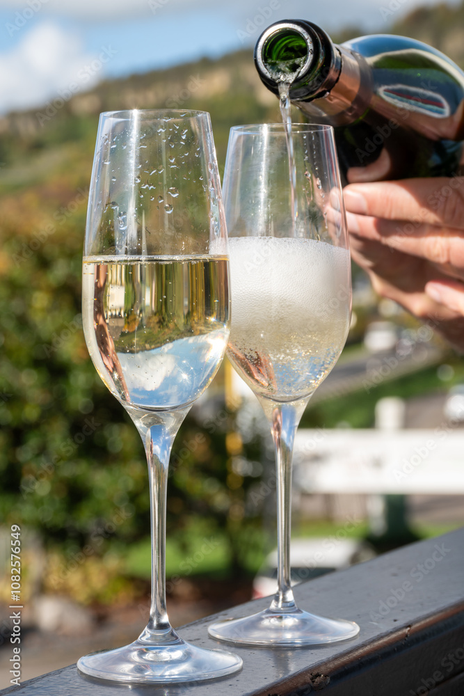Obraz premium Tasting sparkling white wine, traditional champagne method making of cremant in caves on Moselle river valley in Luxembourg, glasses of wine and view on terraced vineyards