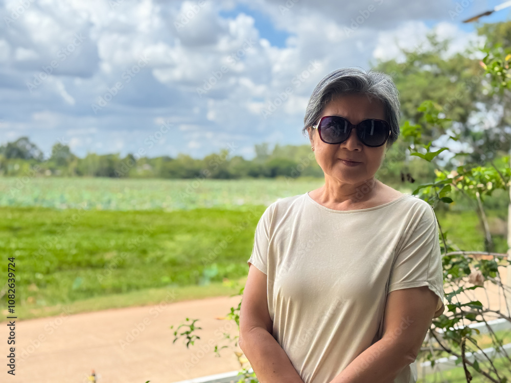 Asian Thai Chinese woman wear sunglasses, smiling and standing over green view at countryside, enjoy holidays traveling in Thailand village. Asian Thai Chinese woman wear sunglasses, smiling and standing over green view at countryside, enjoy holidays traveling in Thailand village.