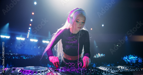 Stylish Girl Performing at a DJ Concert Live on Stage. Talented Music Producer Dancing, Mixing Energetic Dance Hits on Turntables. Young Beautiful Female Engaging with the Crowd photo