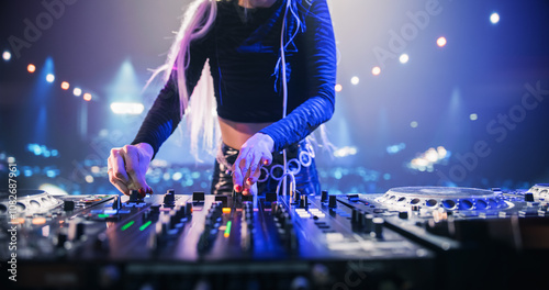 Close Up of an Anonymous Female DJ Performing Live at a Night Club, Using DJ Turntable Decks and Mixer to Play Techno Dance Music at a Rave Party. Pop Music Beats at an EDM Concert on Stage photo