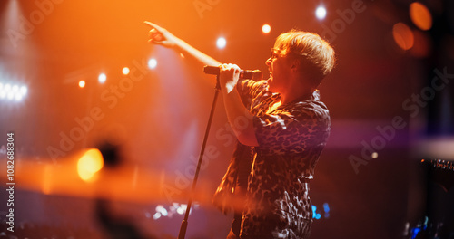 Indie Band Performing Live on Stage, Bringing Their Unique Sound to a Packed Club. Lead Singer with Passion and Energy. Stage Surrounded by Cheering Fans Holding Flashlights photo