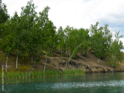 lake with green water surrounded by rocks and birches in Konduki, Russia