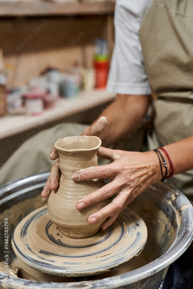A talented woman expertly molds wet clay on a potters wheel, showcasing her craftsmanship. A talented woman expertly molds wet clay on a potters wheel, showcasing her craftsmanship.