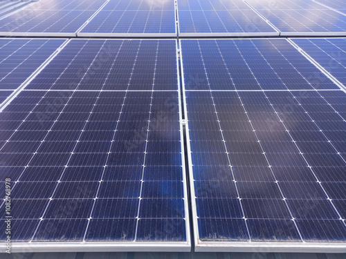 large array of solar panels installed on a rooftop. The solar panels are arranged in rows and are angled to maximize exposure to sunlight. photo