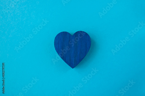 Blue wood heart on the blue fabric background with space for text.