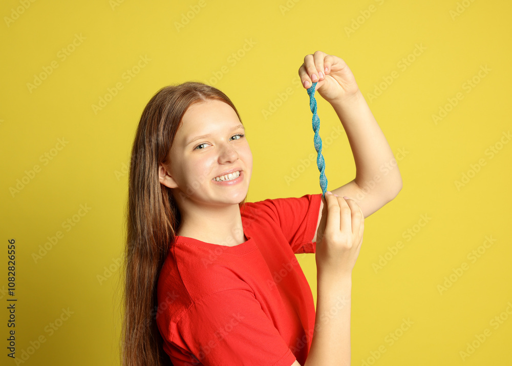Happy teenage girl holding tasty gummy candy on yellow background Happy teenage girl holding tasty gummy candy on yellow background