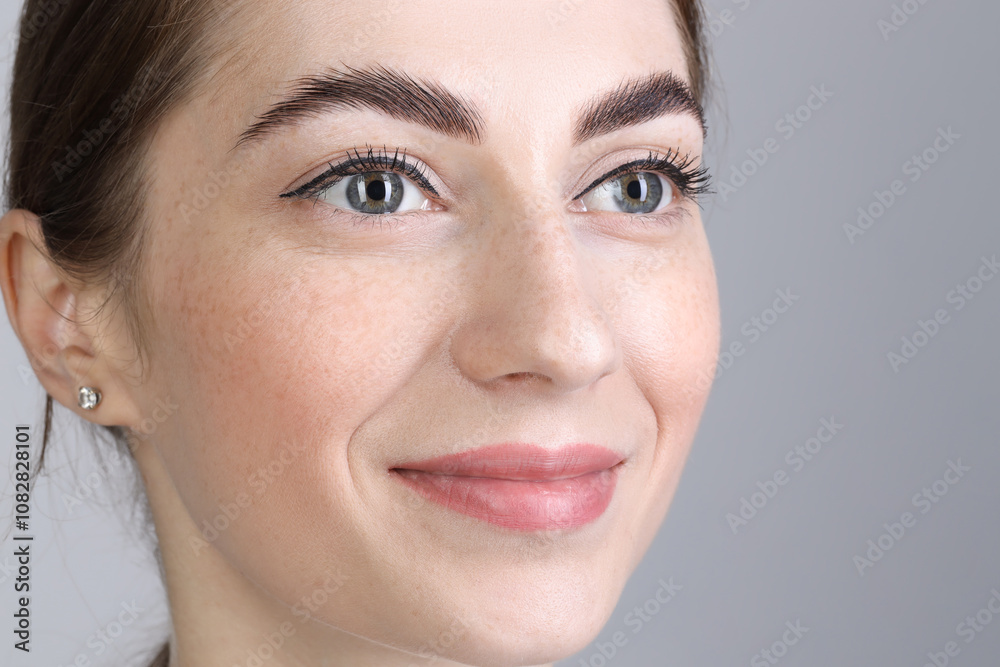 Woman after brow lamination procedure on grey background, closeup Woman after brow lamination procedure on grey background, closeup