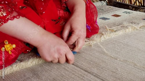 Craftswoman trimming a wool carpet with scissors, showcasing skill and precision in a traditional textile making process