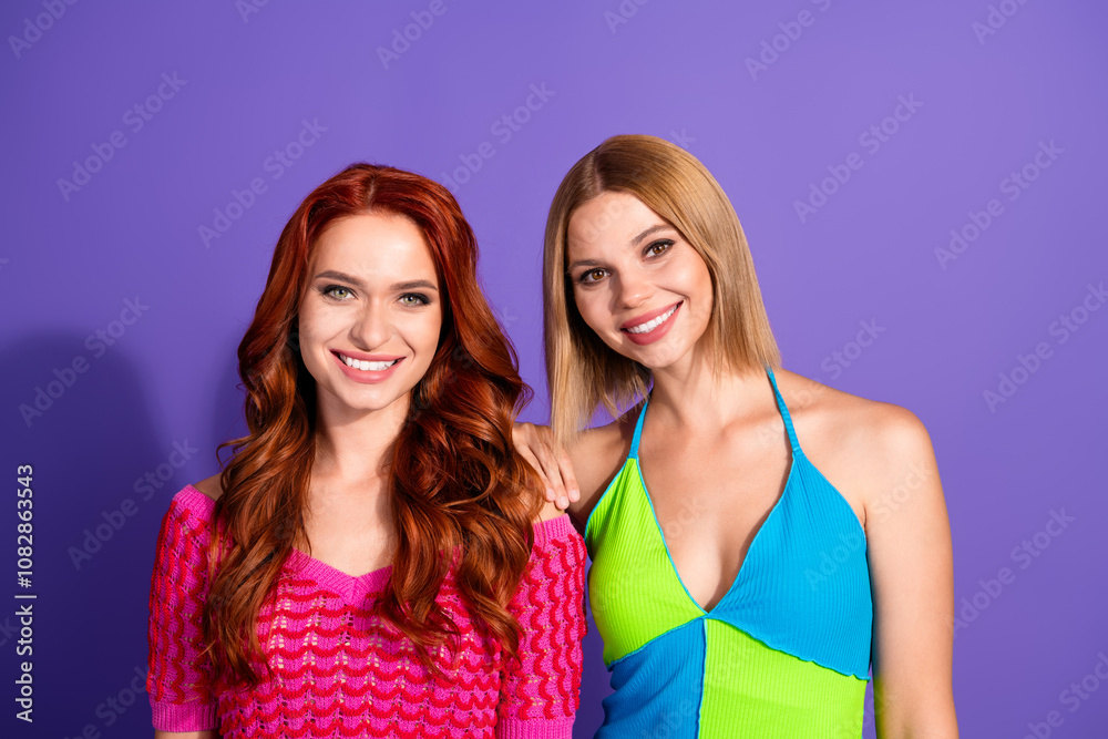 Photo of two pretty gorgeous girls toothy smile cuddle isolated on violet color background Photo of two pretty gorgeous girls toothy smile cuddle isolated on violet color background