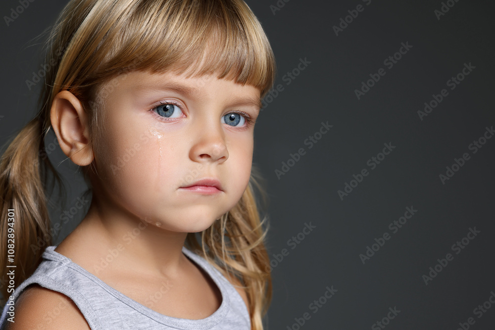 Orphanage concept. Sad little girl on grey background, space for text Orphanage concept. Sad little girl on grey background, space for text