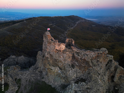  Georgia flag on the top on mountain tower after sunset 