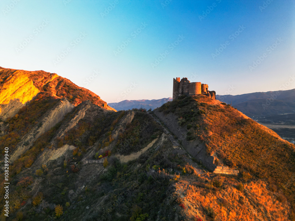 Ancient fantasy tower castle at sunset on desert mountain - drone aerial shot, Ksani, Georgia Ancient fantasy tower castle at sunset on desert mountain - drone aerial shot, Ksani, Georgia