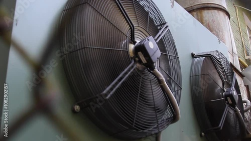 industrial air conditioner extractor fan hanging on the wall outside the building. refrigeration blower running and spinning close up