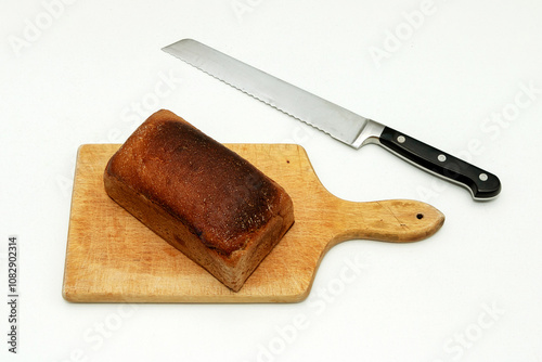 Rye bread loaf on wooden board and knife on a side