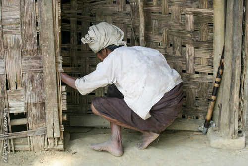 South asian indigenous rural lady in the doorway of her small cottage  photo