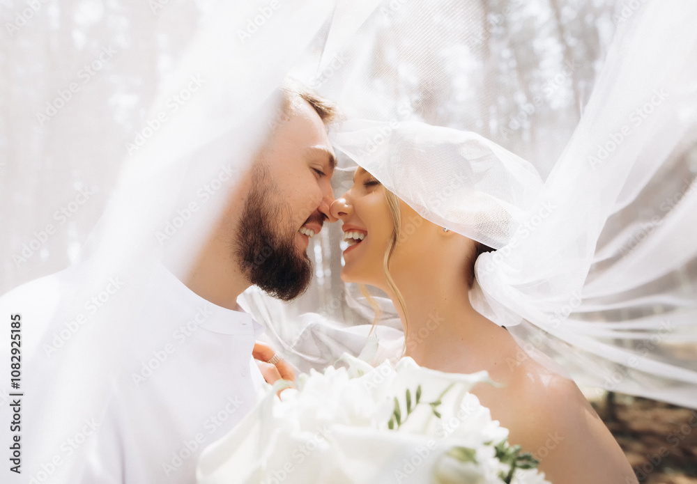 Young wedding couple under veil looking each other Young wedding couple under veil looking each other