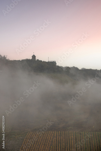 Landscape shot in autumn. a town meanders between a river and autumnal vineyards in the mist. A castle stands on the hill. Zell Mosel, Hunsrück, Rhineland Palatinate photo