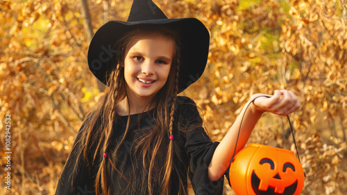 Little girl in scary witch costume at halloween celebrations party in forest. Halloween - traditional american holiday. Kid ready for trick or treat on Halloween night photo