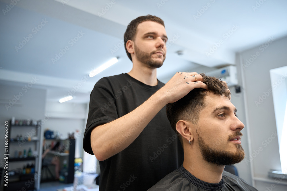Skilled barber applies styling cream to client fresh haircut Skilled barber applies styling cream to client fresh haircut