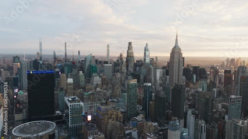 Sunrise illuminating the towering skyscrapers of midtown Manhattan, showcasing the iconic Empire State Building amid a vibrant urban scene