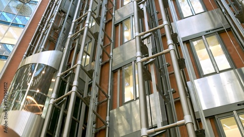 Modern passenger elevator made of metal, glass walls and panoramic views in a new business center. The elevator cabin goes up to the top with a view of the shopping center lobby