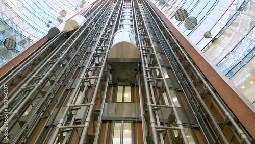 Modern passenger elevator made of metal and glass in the main hall of the new business center. Loaded elevator with people goes down