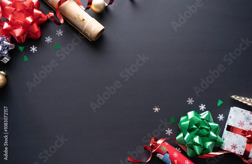 Black background for Christmas with green and red  ribbons and a paper cover decoration. Holidays and celebration season
