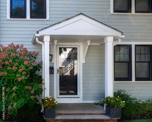 Front entry of a family home with gabled portico and storm door in Brighton, Massachusetts, USA

