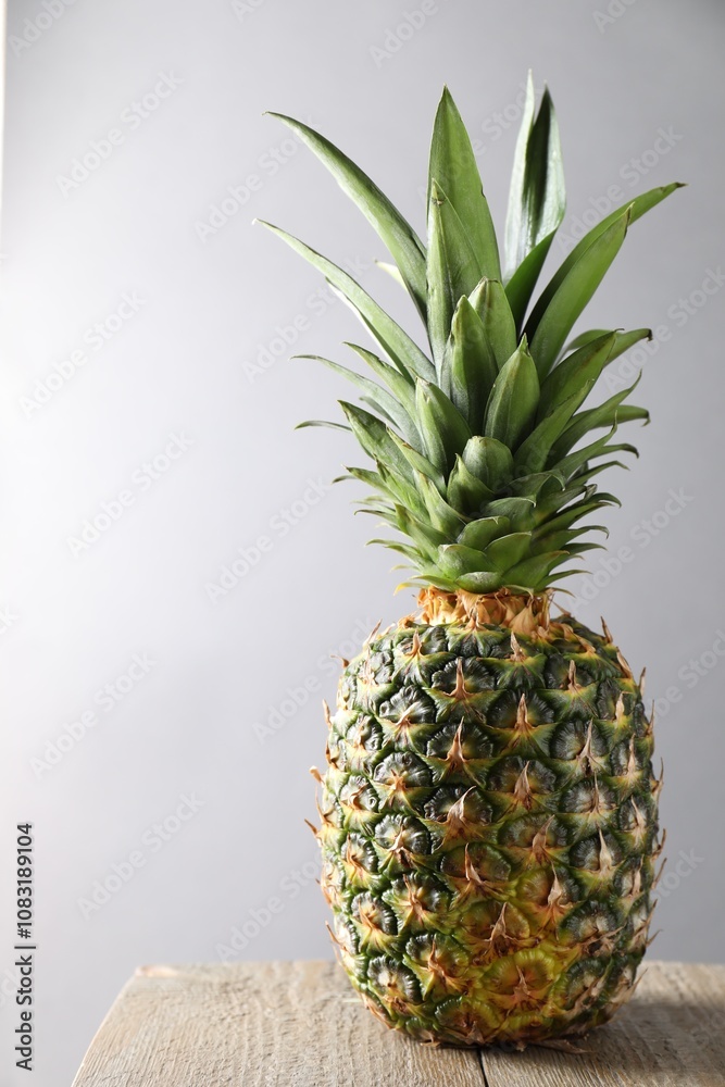 Fototapeta premium Fresh ripe pineapple on wooden table against light grey background