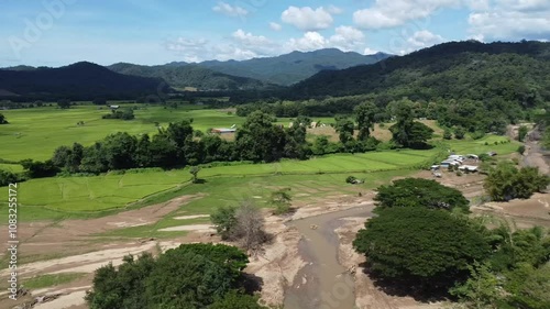 Creek, rice fields and forests surrounded by mountains in northern Thailand