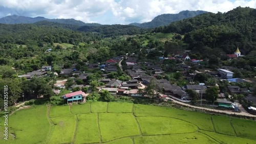 Road with bridge in village filled with trees and mountains in northern of Thailand