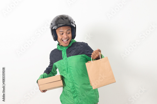 Portrait of Asian online courier driver wearing green jacket and helmet giving craft paper shopping bag and box package. Isolated image on white background photo