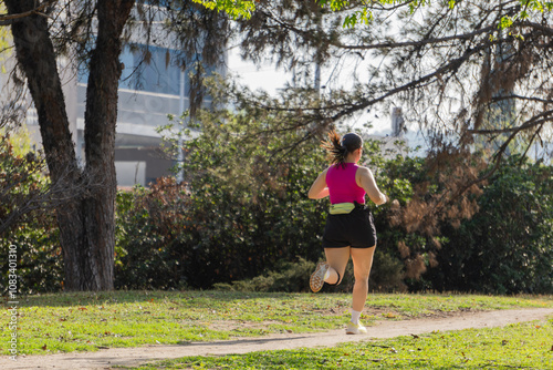 Young woman running outside on a path surrounded by greenery in a park