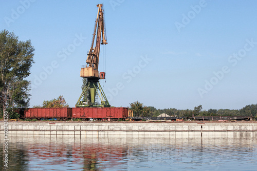 Portal crane and freight railway cars are on the coast in harbor photo