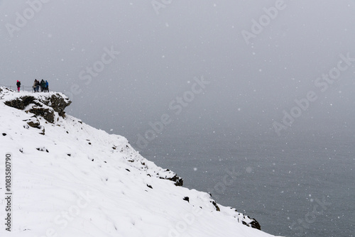 Dyrholaey Lighthouse on the central south coast of Iceland on April 13, 2024. While landscape while it snowing. photo